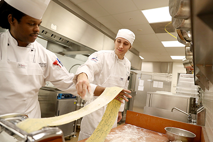 Chef Derek Anders Jr. (left) demonstrates pasta-making techniques to students in his CUL 120 (Classical Kitchen) class.